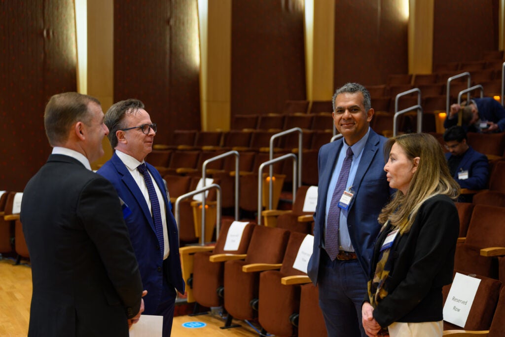 Four people in business attire standing in conversation