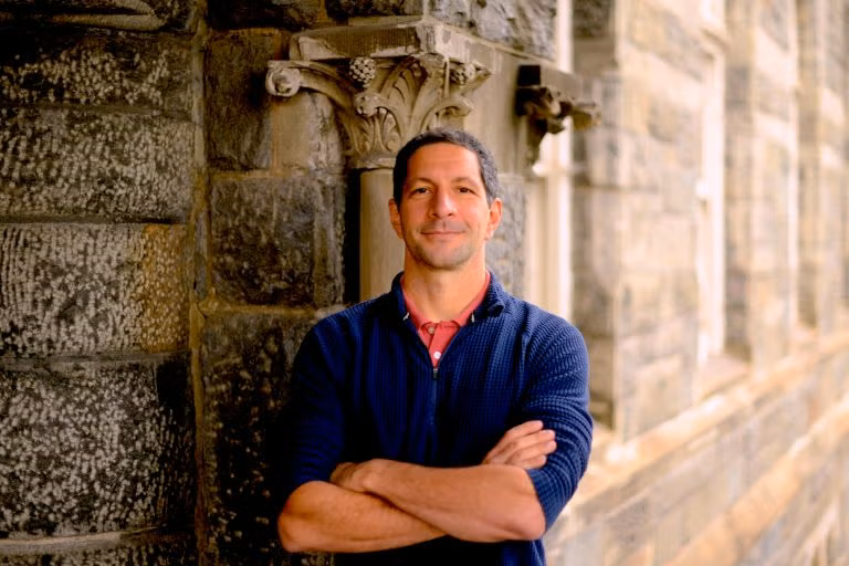 Man in blue shirt by wall